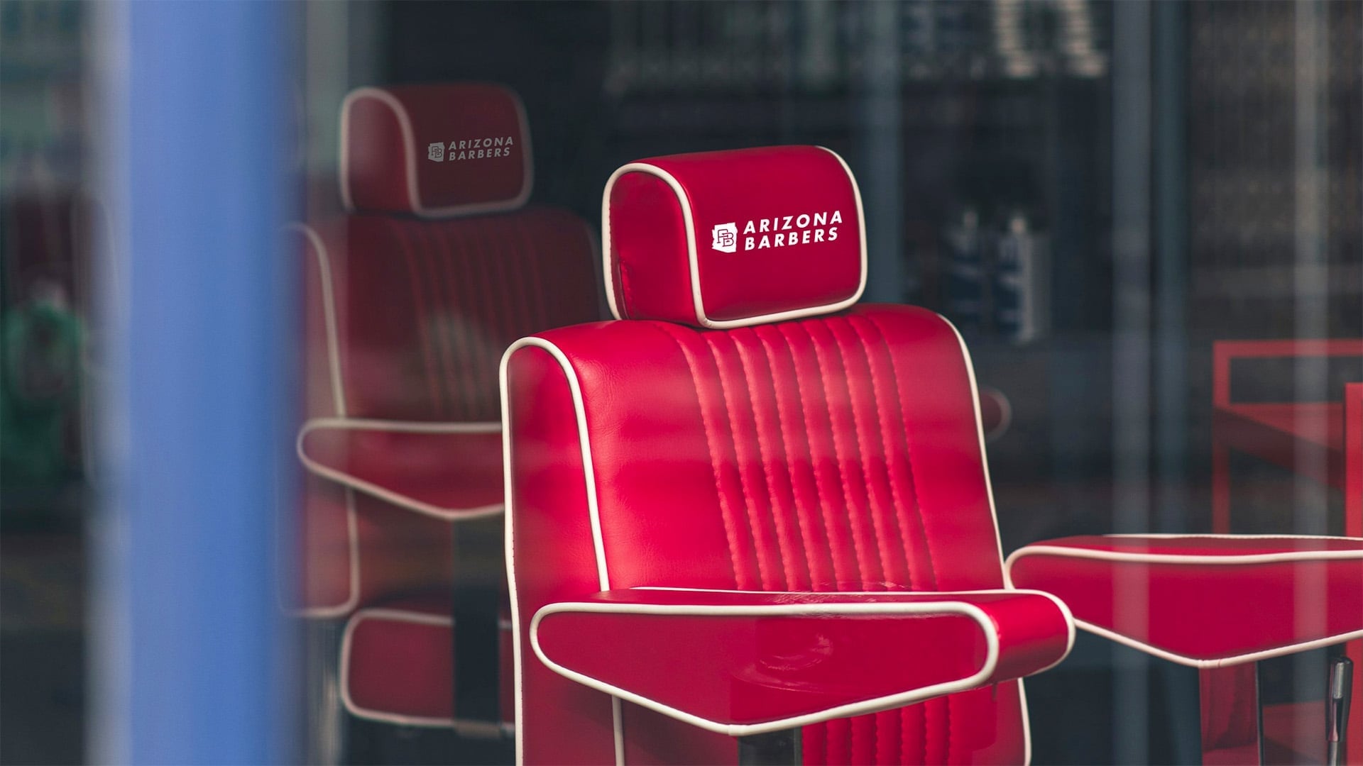 A classic barbershop interior featuring a vintage-style red and chrome barber chair in front of a mirrored backbar.
