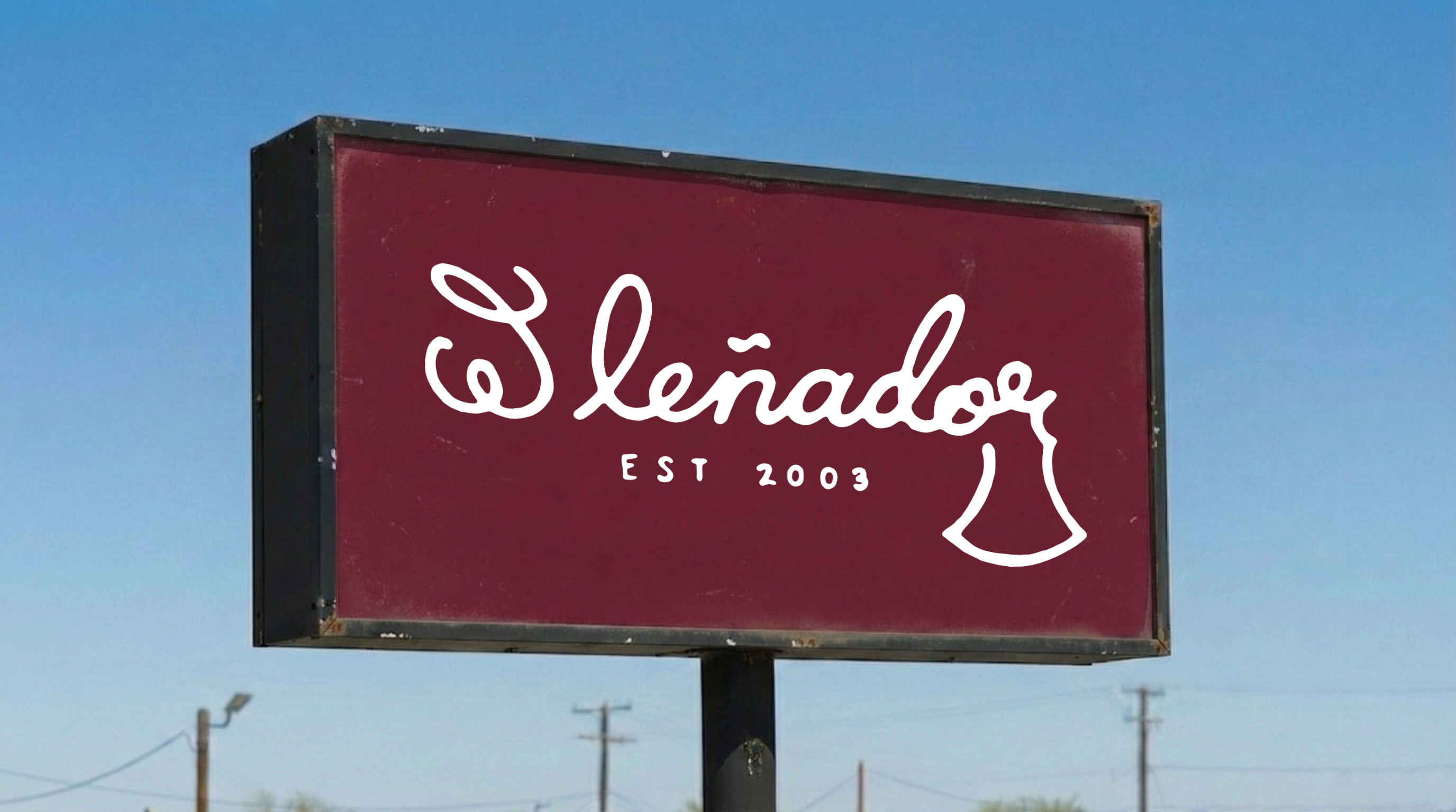 A rectangular sign with a maroon background and black frame, showcasing the text 'Leñador' in white cursive script. Below.